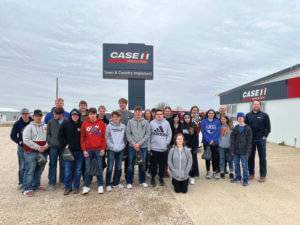 Large group of students stand outdoors in front of Case IH sign